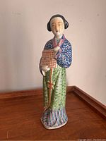 Full front view of the porcelain lady figurine showing detailed colors and patterns on clothing and face.
