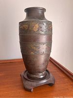 Full view of the Chinese bronze vase on wooden stand showing shape, color and overall condition.