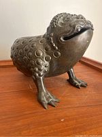 Front view of the antique bronze toad censor showing detailed circular bumps and open mouth slit.