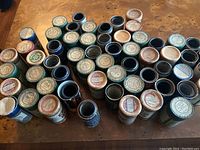 Overhead view of the 54 Edison cylinder record containers arranged closely on a wooden table showing a variety of label colors and designs.