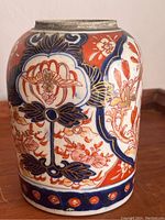 Side view of Japanese Satsuma vase displaying detailed floral patterns in red, blue, and gold on cream ceramic.