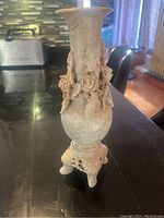 Full view of large carved vase showing floral carvings, tripod base, and general shape