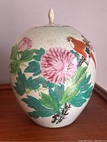 Full view of the ginger jar showing the pink flower and orange bird motif against a white background