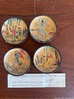 Four round porcelain snuff dishes arranged on wooden surface with paper label