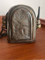 Front view of old Tibetan prayer box with detailed embossed panel showing Tibetan motifs.