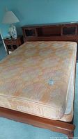 Full view of wooden bed frame with attached headboard and mattress showing overall condition and style