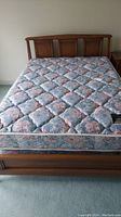Full front view of wooden bed frame with floral mattress showing overall condition and style.