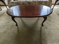 Front-facing view of the oval wooden coffee table highlighting wood grain and curved legs.