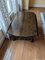 Top view of wooden drop leaf coffee table showing worn surface with scratches and scuffs.