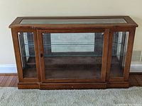 Front view of the wood display case showing glass paneled doors and interior glass shelf.