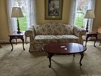 Living room setting with the two end tables positioned on either side of a floral upholstered sofa, alongside matching lamps and a coffee table.