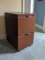 Front view of the two drawer wood look file cabinet with handles and lock holes.