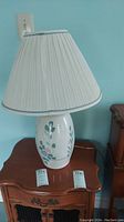 Side view of the ceramic lamp showing floral pattern and pleated lampshade