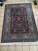 Full top-down view of the rectangular area rug laid on tile floor showing the overall pattern, color, and fringe.