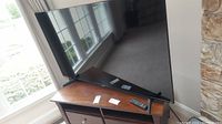 Front view of the 65-inch TV on wooden stand, remote on table