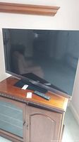 Full front view of the Sony Bravia 46 inch TV showing the full screen and base stand, placed on wooden cabinet.
