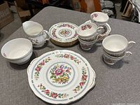 Duchess Nanking tea set displayed on gray surface: 2 cups stacked, 2 saucers, 2 bread plates, serving plate, sugar bowl, and creamer.