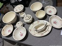 Top down view of the entire china set laid out on table showing all pieces including platters, bowls, teapot, sugar bowl, creamer, and plates