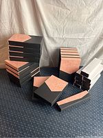 Overall view featuring stacks of various-sized black and peach jewelry boxes on a patterned surface.