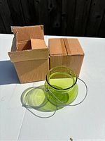 Green glass jar displayed outside of its packaging, showing its translucent green color and metal handle.