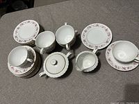 Full view of the tea set including cake plates, teacups, saucers, sugar bowl, and creamer arranged on a table.