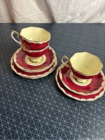 Full view of 2 stacks of Royal Albert teacups, matching saucers and dessert plates on geometric background.