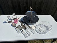 Wide shot showing all items included: two-tier cake platter, crystal bowl, silver serving utensils with acrylic handles, Royal Doulton trinket dish, and metal decorative items