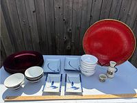 Overview of sushi plates, soy bowls, sake set, and red charger plates on table with ruler for scale.
