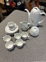 Full view of coffee set with all items arranged on table showing cups, saucers, coffee pot, creamer, and sugar bowl.