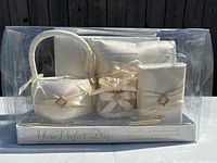 Front view of the unopened wedding set packaging showing the coordinated ivory satin flower basket, ring pillow, guestbook, pen, and garters.