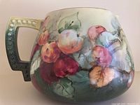 Side view of the hand painted water pitcher showing detailed apple clusters and textured handle.