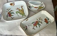 Three-piece set of Royal Worcester Evesham dinnerware including two lasagne-style casserole dishes and one gravy boat with attached underplate, showing fruit and vegetable decoration.