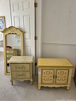 Photo of two vintage night stands and tall dresser mirror. One night stand with drawers, one cabinet night stand, and arched framed mirror standing beside them.