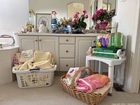 Wide view of bathroom floor with baskets of towels, toiletries on countertop, and floral arrangements