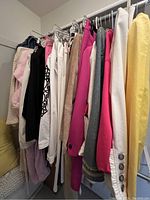 Rack of assorted women's coats, pants, and robes in multiple colors hung on hangers