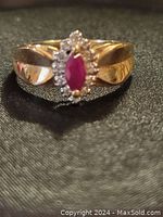 Front view of ring showing marquise ruby and diamond halo on black background
