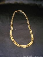 Full view of 14K gold link necklace on black background