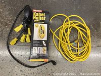 Yellow Jacket extension cord coiled with Stanley Power Squid and its box on concrete floor.