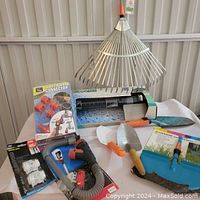 Image showing gardening tools including metal rake, hand trowels, hose connectors and spray nozzle, and garden kneeling pad.
