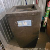 Full view of dark brown rectangular rain barrel with screen guard on top and visible label on the front.