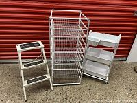 Full view of all three items side by side: metal mesh drawer cart, plastic tray cart on wheels, and metal step stool