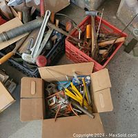 Overview photo of various hand tools scattered and in boxes, includes pipe wrench, mallet, screwdrivers, clamps, and other tools.