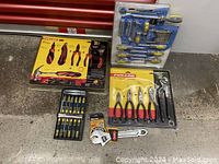 Overview of multiple tool sets, including Fuller 28-piece set, Fuller 5-piece plier set, ratchet wrench, and screwdriver bit sets on floor.