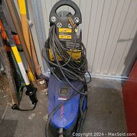 Front angled view of the pressure washer showing handle, hose coiled at the top, and general good condition.