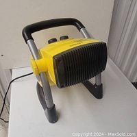Front and side view of yellow Stanley portable electric ceramic heater positioned on white surface showing control knobs and pivot frame.