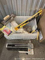 View of all items including manual tile cutter, bags of tile spacers, yellow spirit level, notched trowel, tile clippers, and boxed cutter parts.