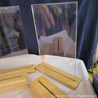 Six frames arranged showing wood bases with slots and clear acrylic or glass panels in place and separately on table.