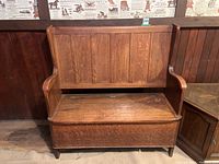 Front view of the wooden storage bench showing paneled backrest, armrests, and hinged seat.