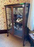 Front perspective view of oak display cabinet showing curved glass doors and interior contents