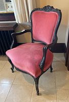 Left side angle showing ornate carved dark wood frame, red upholstery with padded armrests and seat.